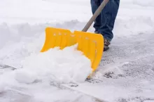 Man shoveling snow in driveway during winter snowstorm
