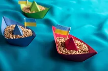 Ships with Ukrainian wheat grain made of paper concept