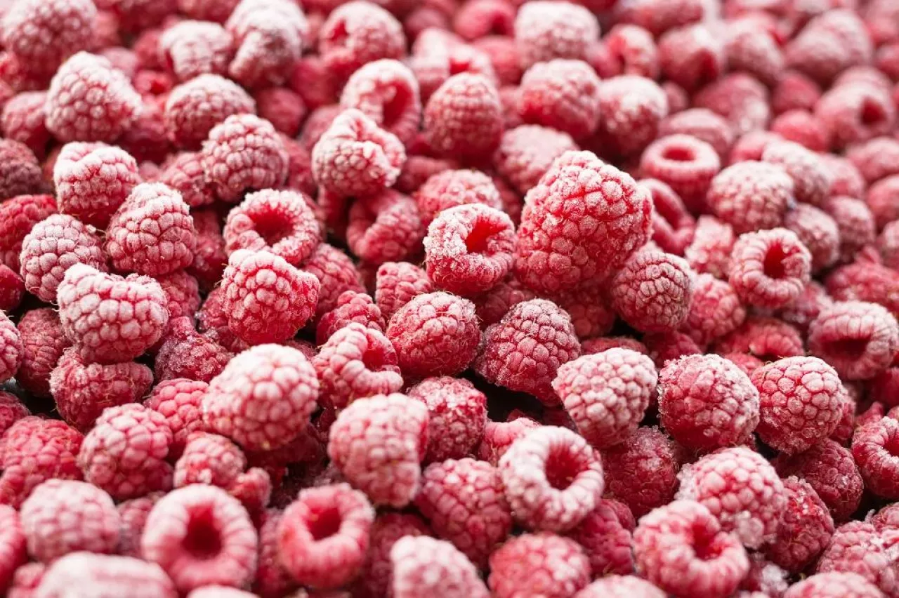 Frozen red raspberries background. Shot at angle