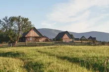 Village houses on hills with green meadows in summer day. House of shepherds in mountains in carpathian.