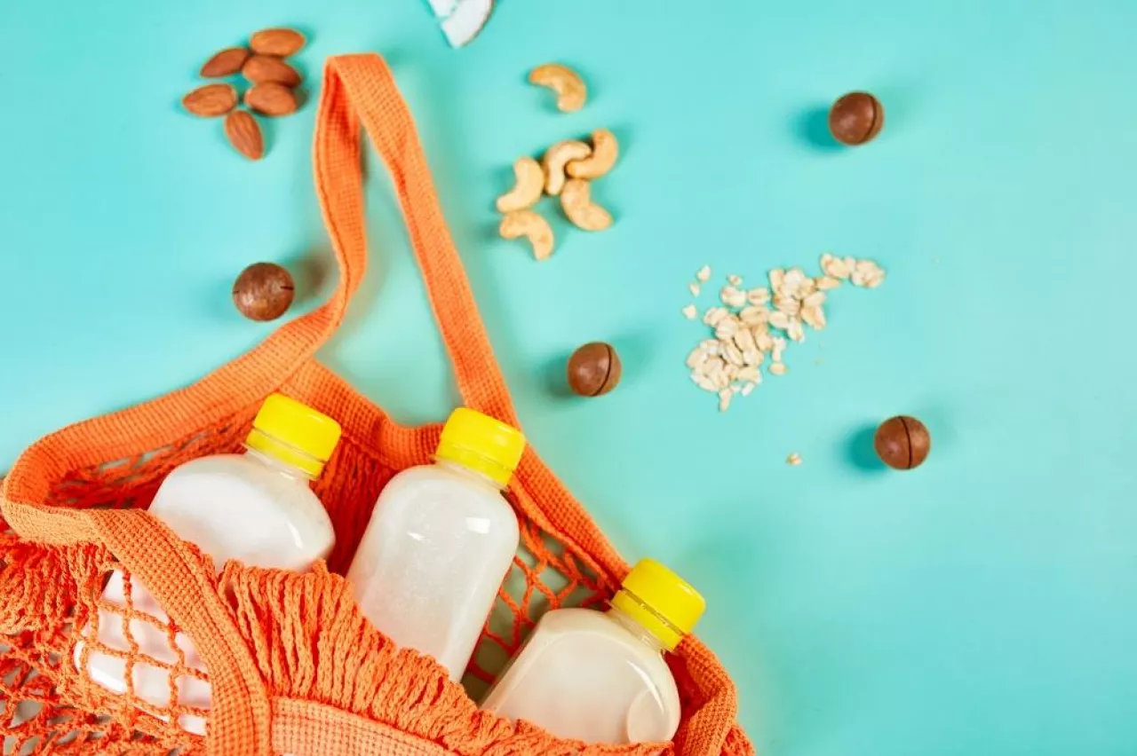Grocery, shop Various vegan plant based milk, non-dairy milk, alternative types of vegan milks in bottle in shopping bag on a blue background, flat lay, top view with copy space