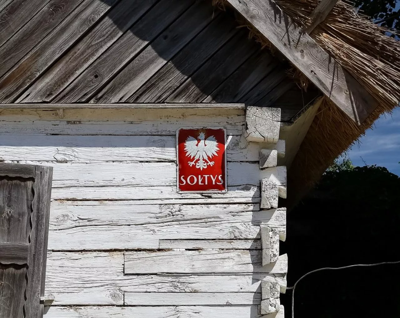Sierpc, Poland - July 2022A red plate with a name of a village administrator ”Soltys” on a facade of a wooden village hut in the Museum of the Mazovian Countryside in Sierpc. Selected focus.