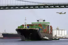 Transport - a large container ship pass under a road bridge with trucks on it with an aircraft coming in to land at a nearby airport.
Port of Long Beach, California, USA.