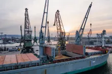 Black Sea Grain Initiative 2023 grain Deal. Silhouettes of port cranes during the loading of grain on a bulk carrier at sunset during the golden hour. Panoramic flight from a drone