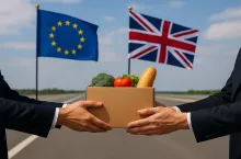 Symboliczne zdjęcie przedstawiające moment przekazania paczki z produktami rolno-spożywczymi między przedstawicielami Unii Europejskiej i Wielkiej Brytanii. W tle widoczne flagi obu stron. Grafika ilustruje temat barier handlowych i negocjacji w sprawie porozumienia SPS po Brexicie.