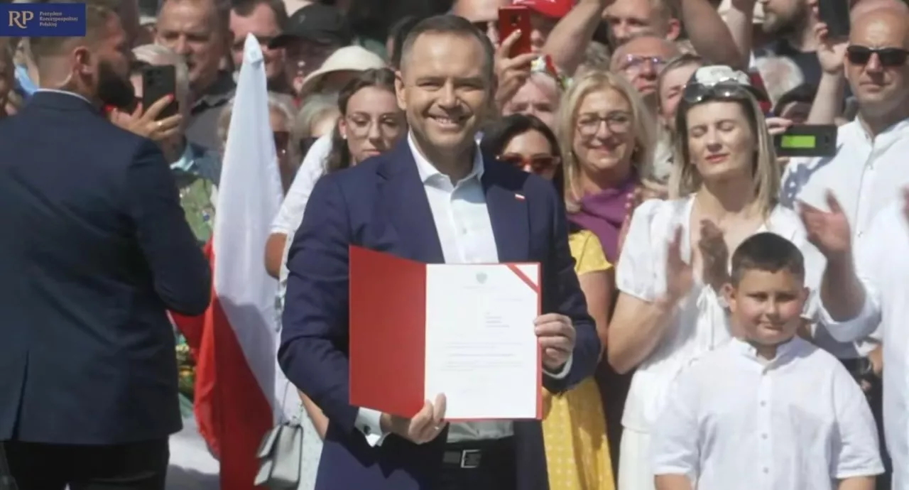 Prezydent RP Karol Nawrocki prezentuje podpisany projekt ustawy ”Ochrona polskiej wsi” podczas wizyty w Krąpielu w powiecie stargardzkim. W tle zgromadzeni mieszkańcy. Zrzut ekranu z transmisji na Facebooku Kancelarii Prezydenta RP.