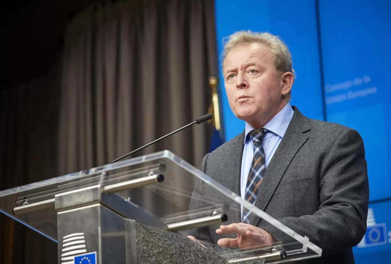 Były komisarz UE ds. rolnictwa przemawia podczas konferencji prasowej przy mównicy z logo Rady Unii Europejskiej. W tle niebieskie tło i flaga UE.