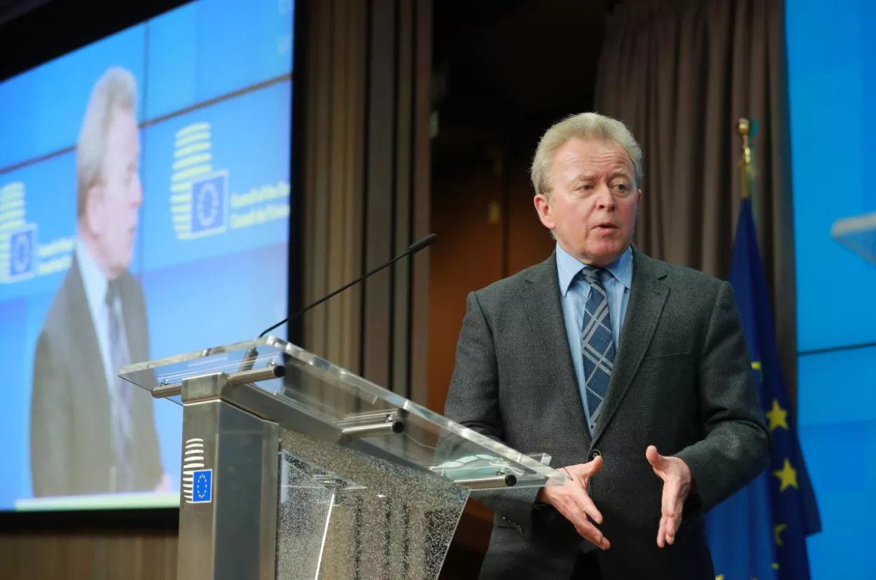 Były komisarz UE ds. rolnictwa Janusz Wojciechowski podczas konferencji prasowej w siedzibie Rady Unii Europejskiej w Brukseli. W tle logo Rady UE i flaga unijna.