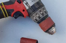 wkrętarka oraz papier ścierny, leżące na płaskiej powierzchni