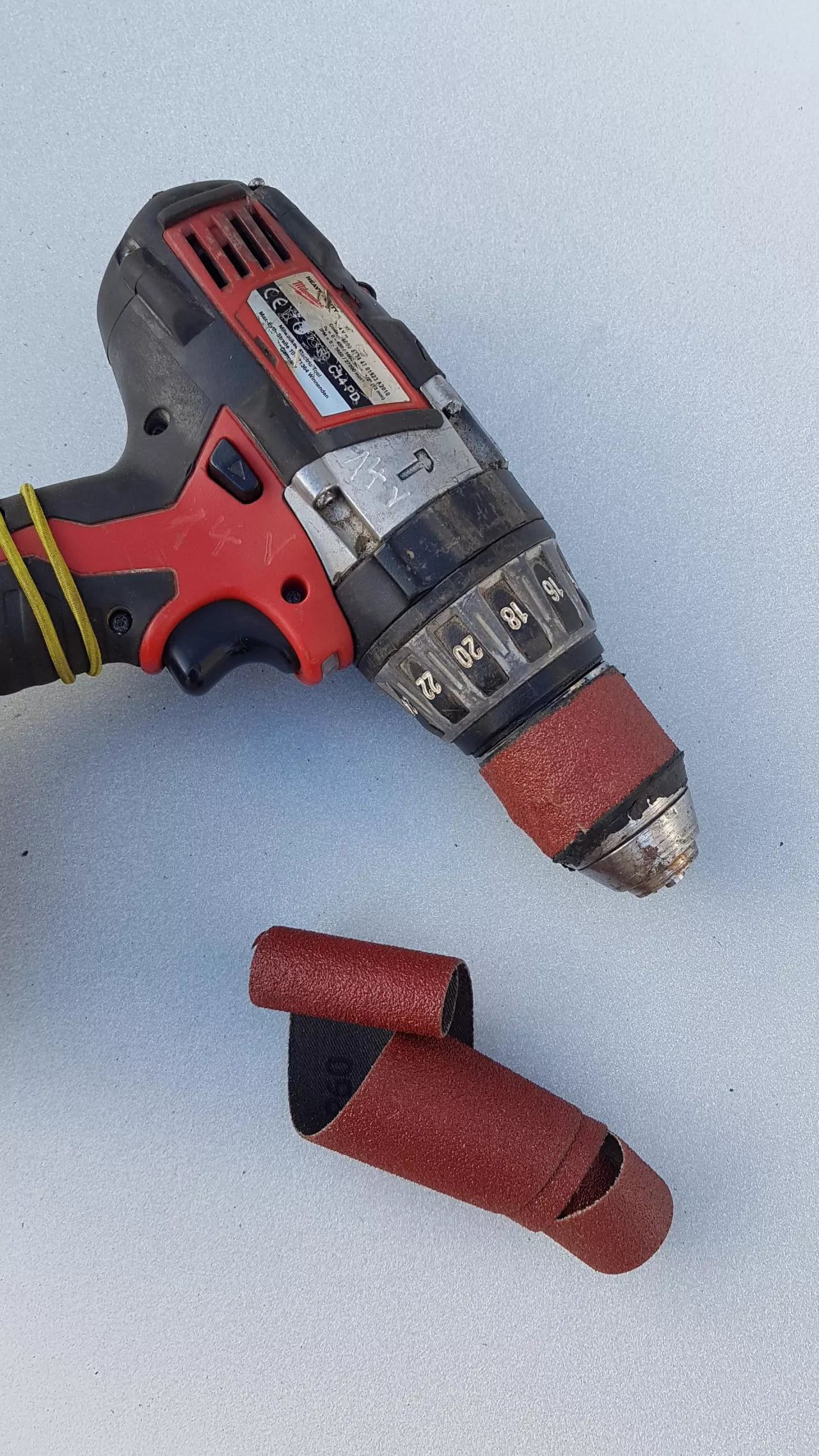 wkrętarka oraz papier ścierny, leżące na płaskiej powierzchni