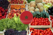 Drewniane skrzynki z warzywami i owocami typowymi dla produkcji w Maroku – pomidorami, ogórkami, papryką, melonami i winogronami. Zdjęcie ilustracyjne, z naniesioną flagą Maroka.