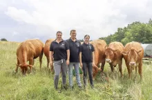 Rolnicza rodzina Kohlmannów stoi na pastwisku z bydłem limousine w tle