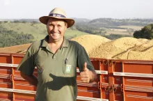 Zadowolony rolnik na tle przyczepy pełnej zebranej soi