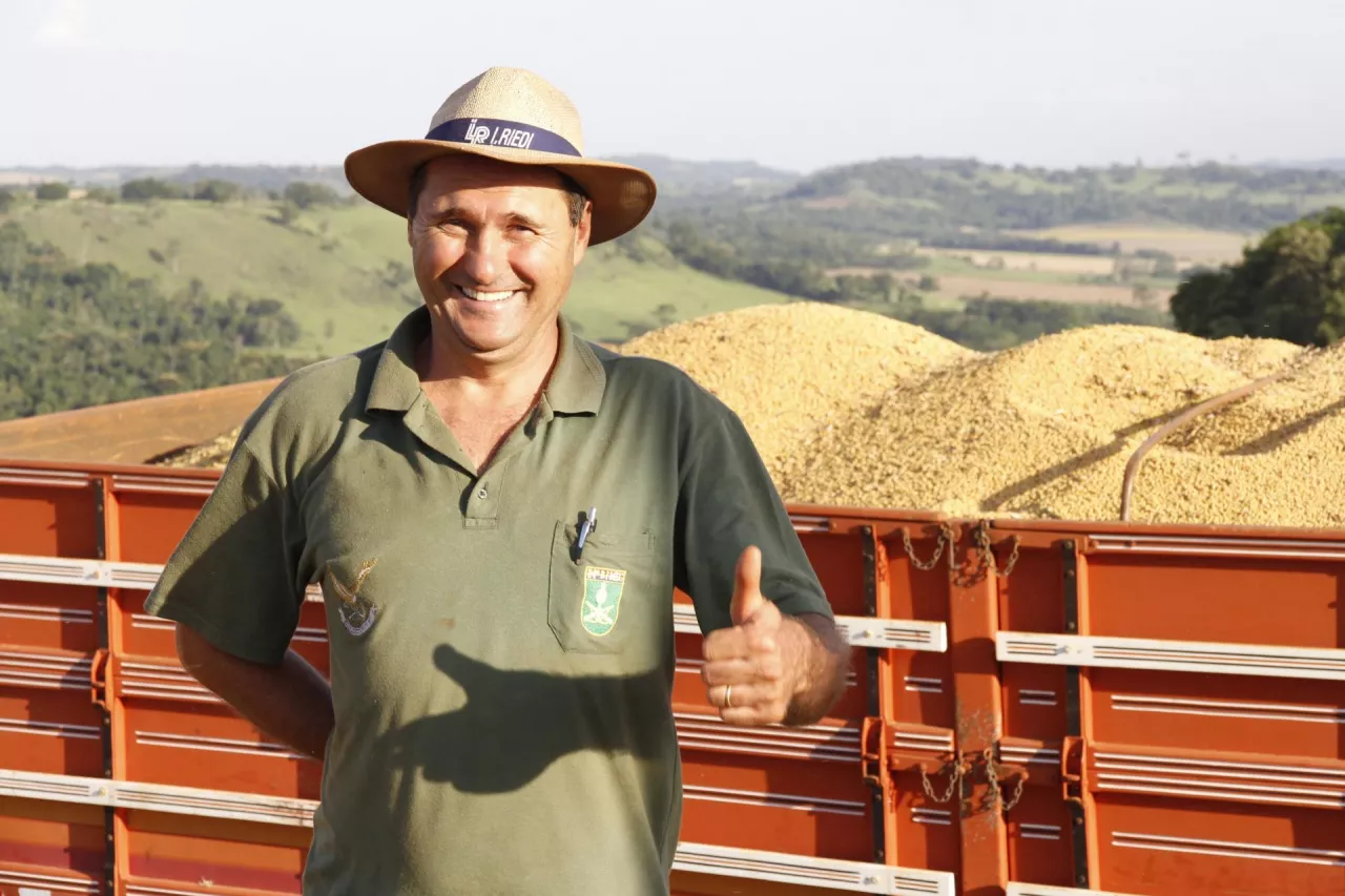 Zadowolony rolnik na tle przyczepy pełnej zebranej soi