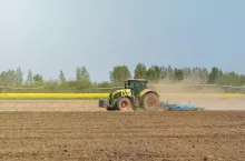 Ciągnik Claas z kultywatorem pracuje w polu uprawnym