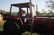 mężczyzna i chłopiec siedzą w kabinie czerwonego ciągnika IMT-542