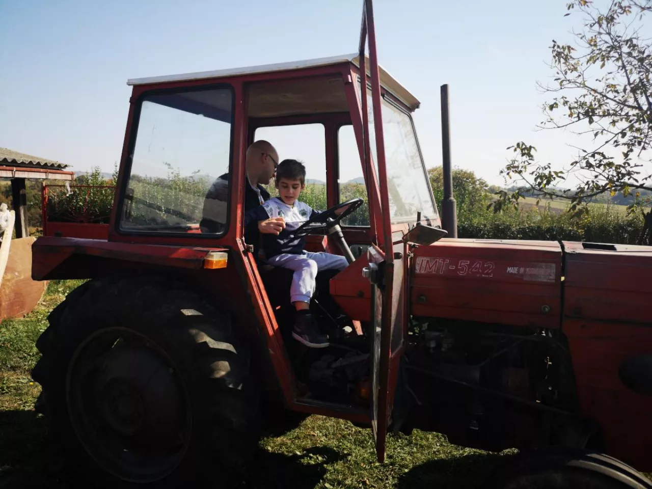mężczyzna i chłopiec siedzą w kabinie czerwonego ciągnika IMT-542