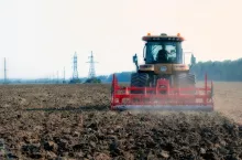 Ciągnik z przyczepionym agregatem uprawowym jedzie przez pole