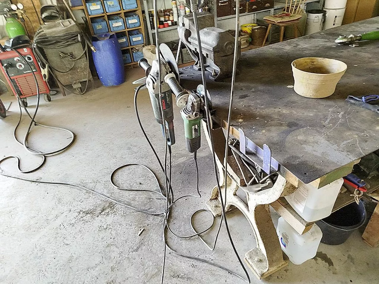 Uchwyty do szlifierek kątowych zamocowane do boku blatu stołu warsztatowego wykonane z blachy