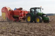 Zbiór ziemniaków na polu. Traktor z maszyną rolniczą podczas prac w gospodarstwie.