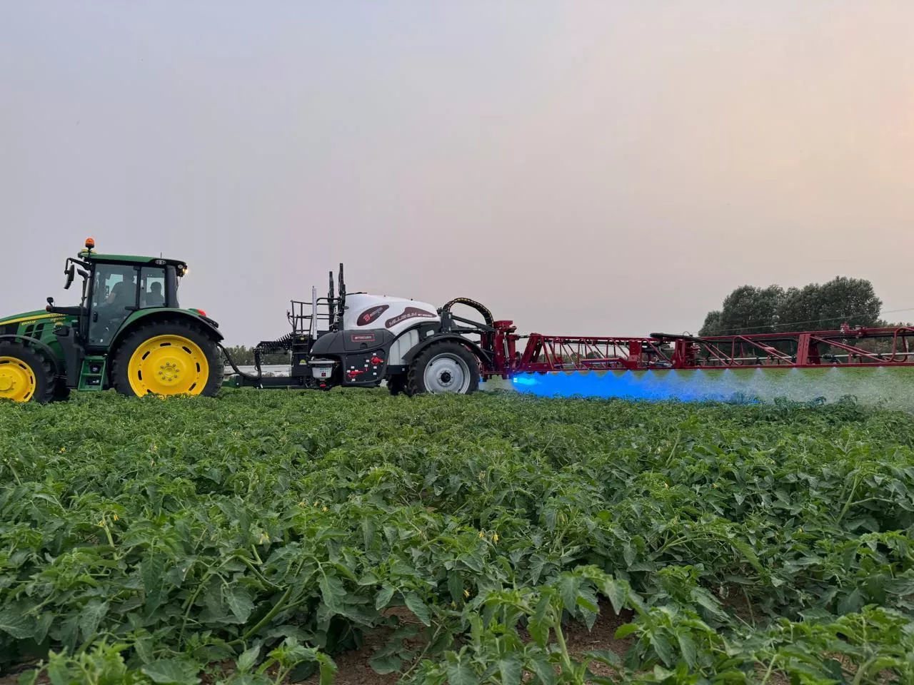 Opryskiwacz producenta Agroma Millenium ET/ST/T przyczepiony do ciagnika podczas pracy w polu