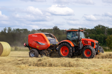 ciągnik Kubota na polu z zaczepioną prasoowijarką