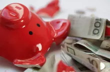 Rozbita skarbonka w kształcie świnki leży na banknotach polskich złotych