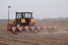 ciągnik z zaczepionym agregatem uprawowo-siewnym pracuje na polu podczas siewu kukurydzy