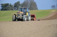 Ciągnik z zaczepionym siewnikiem na polu podczas prac polowych
