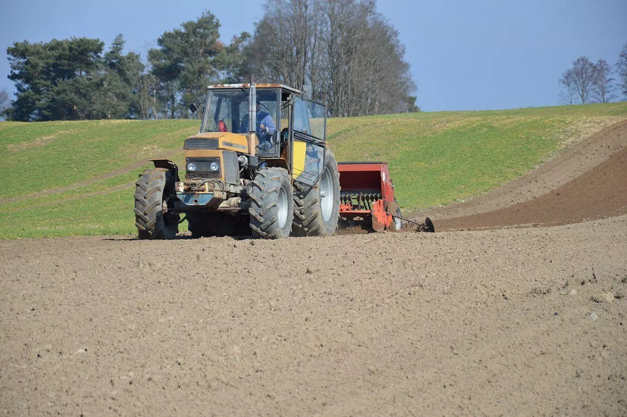 Ciągnik z zaczepionym siewnikiem na polu podczas prac polowych