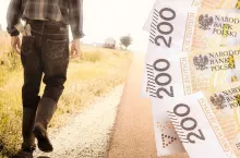 Rolnik idzie drogą wzdłuż pola uprawnego. Na drugim planie pieniądze