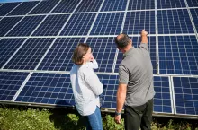 Happy father showing his wife and little son new solar panels. Young family getting acquainted with modern innovation. Back view of young woman with cute child and man looking at solar panels.